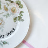 Vintage Wandteller „IRGENDWAS IST IMMER" – handbemalte Statement-Wanddeko aus Porzellan